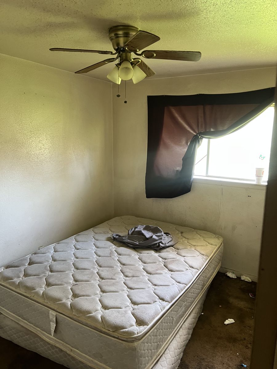 Bedroom with a stained mattress and stained carpet in a Houston 77091 house bought as-is