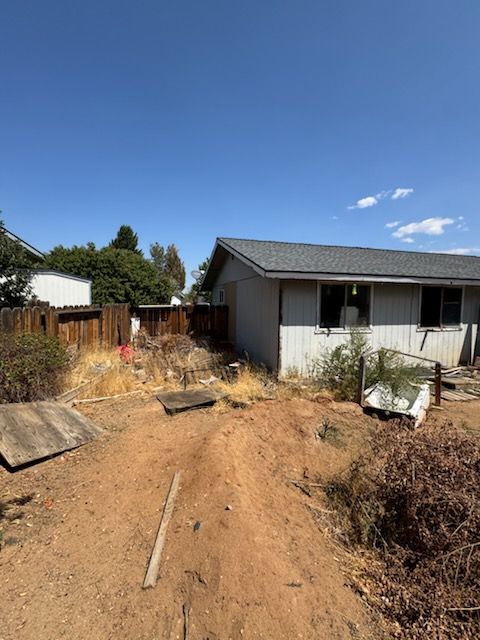 Overgrown dirt backyard of a Carson City 89705 house bought as-is